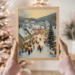 Woman holding a wooden-framed Christmas Village art with glowing holiday lights in the background. Cozy festive vibes.