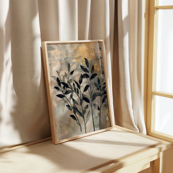 A framed botanical painting with dark leaves on an abstract background rests on a beige table. This neutral wall art adds a serene touch to Japandi-inspired, modern home decor.