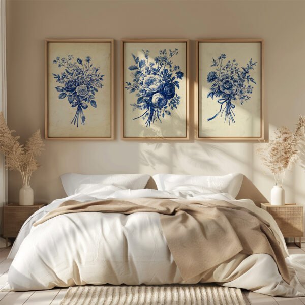 Cozy bedroom with a white bed, beige throw, and three framed Antique Blue Toile Prints of blue floral designs hanging on the wall.