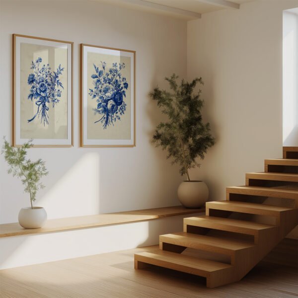 Minimalist room with wooden stairs, potted plants, and two framed Antique Blue Toile Prints of blue botanical florals hanging on a cream wall.