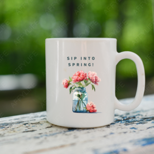 A white mug on an outdoor table features a watercolor floral vase and the phrase "Sip into Spring." This is a creative use of clipart for seasonal drinkware.