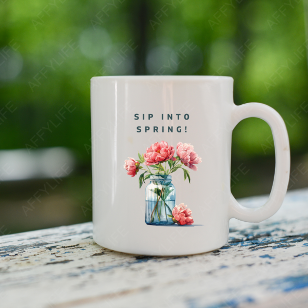 A white mug on an outdoor table features a watercolor floral vase and the phrase "Sip into Spring." This is a creative use of clipart for seasonal drinkware.
