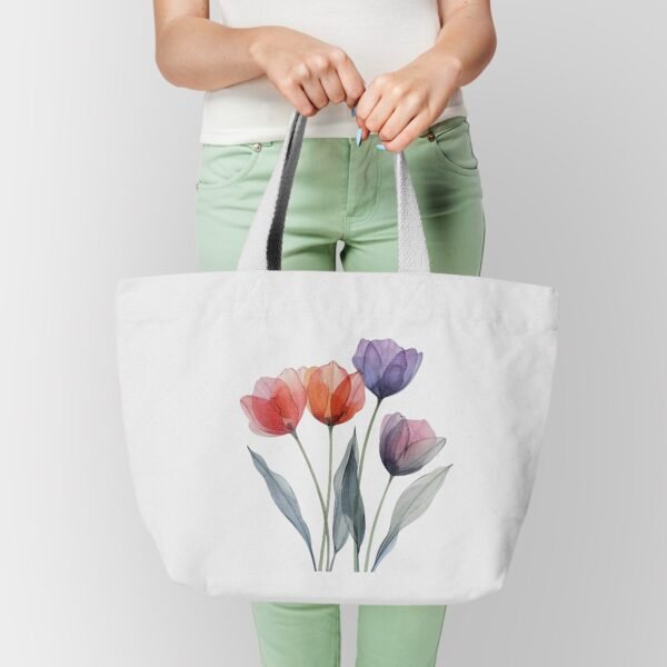 A person holding a white tote bag featuring red, orange, and purple watercolor tulips, paired with a white shirt and mint green pants.