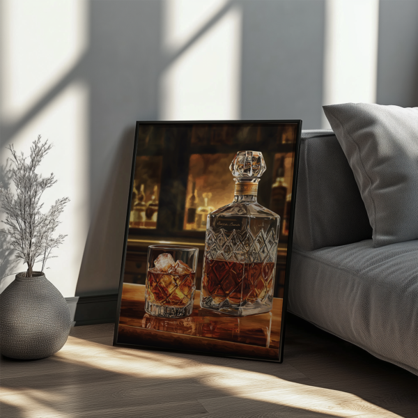 A framed Bourbon Wall Art print of a decanter and glass with amber liquid leans against a couch on a wooden table. Soft light casts gentle shadows, enhancing the warm and inviting atmosphere.