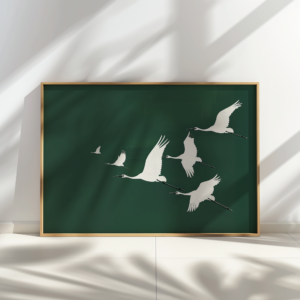 Framed Japandi Wall Art featuring white cranes in flight on a deep green background. Soft shadows cast on the wall create a serene and elegant atmosphere.