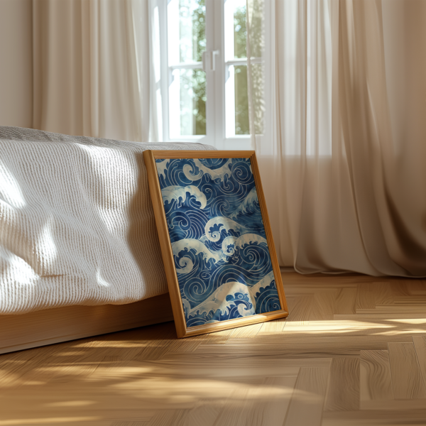 Framed Blue Japandi Wave Wall Art painting of swirling ocean waves leans against a wooden floor near a sunlit window and bed with crisp white linens and light curtains.