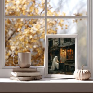 Cozy scene with books and a mug by a window, featuring framed Halloween Ghost Art of a cartoon ghost at a rustic table. Autumn leaves visible outside.